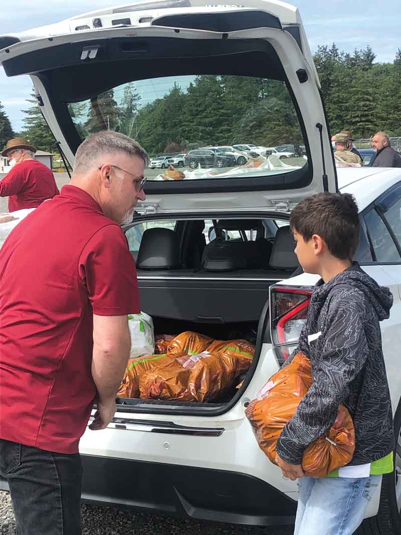 WSPC commissioner Marvin Wollman and Owen Reed, son of commissioner Jordan Reed, load potatoes into a car at one of several potato distribution events held throughout the state.